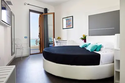 a bedroom with a large bed with blue pillows at Hotel La Battigia in Alcamo Marina