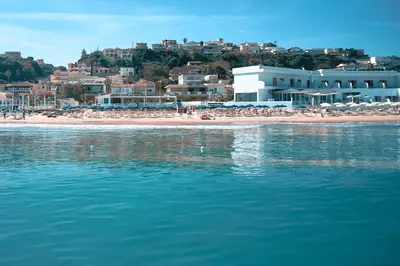 a beach with umbrellas and people on the beach at Hotel La Battigia in Alcamo Marina