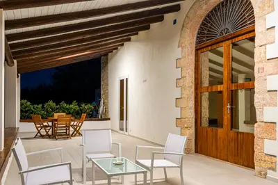 a patio with white chairs and a glass table at Scialari Country House in Castellammare del Golfo