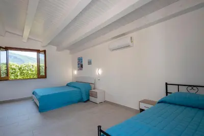 a bedroom with two beds and a window at Scialari Country House in Castellammare del Golfo