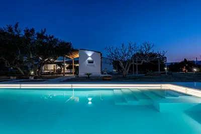 a swimming pool in front of a house at night at Scialari Country House in Castellammare del Golfo