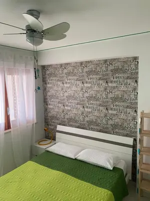 a bedroom with a green bed and a brick wall at La Casetta Blu al Mulino in San Vito lo Capo