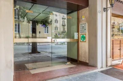 a glass door of a building with a reflection of a street at GuestHost - Teatro Politeama and Teatro Massimo Cozy Apartment in Palermo