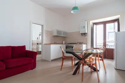 a living room with a red couch and a table and chairs at Quattro Canti by DomuSicily in Palermo
