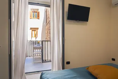 a bedroom with a bed and a window with a tv at Open Sicily Residence - Central Apartments Near Quattro Canti in Palermo