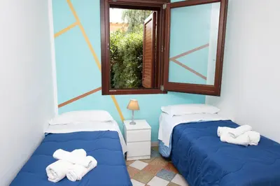 two beds in a room with a window at Villa Morici con ampio giardino in San Vito lo Capo