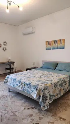 a bedroom with a bed with a blue and white comforter at Amunì rooms and suite LT in Palermo
