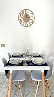 a dining room table with chairs and a clock on the wall at La Casetta sul Golfo in Sferracavallo
