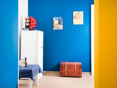 a blue room with a table and a white refrigerator at Palermo Centro - I Pastelli di Van Gogh in Palermo