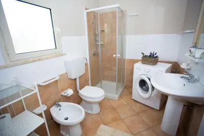 a bathroom with a toilet sink and a washing machine at Villa Dora con piscina in Trappeto