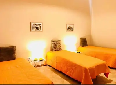 two beds in a room with orange sheets at Villa Dora con piscina in Trappeto