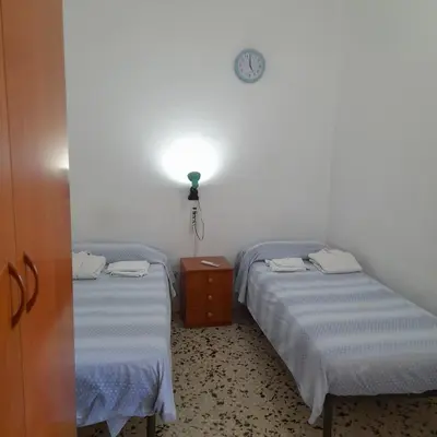 two beds in a room with a light on the wall at Desire'- Le Caprice in Palermo
