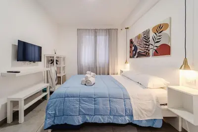 a white bedroom with a blue bed and a desk at Tarzanà 11 apartment - Cala di Palermo in Palermo