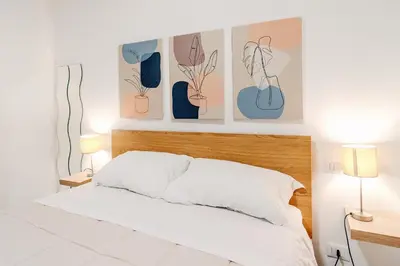 a bedroom with a bed and some pictures on the wall at Tarzanà 11 apartment - Cala di Palermo in Palermo