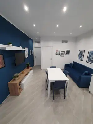 a living room with a table and a blue couch at Airport Home TUREI & BRINGO Car Rental in Cinisi