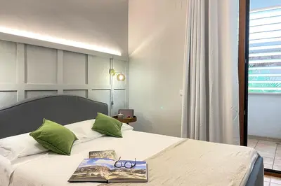a bed with a book and pair of glasses on it at Il Mare in una Stanza by DomuSicily in Mondello
