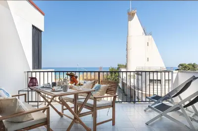 a balcony with a table and chairs and a lighthouse at Vacanze al Mare by DomuSicily in Mondello