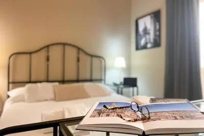 a book and glasses on a glass table next to a bed at Mondello in Terrazza by DomuSicily in Mondello