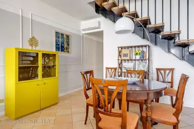 a dining room with a yellow cabinet and a table and chairs at Mondello in Terrazza by DomuSicily in Mondello