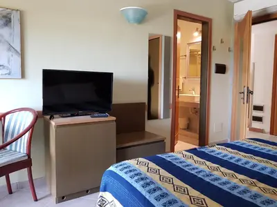 a bedroom with a bed and a flat screen tv at Addaura Village e Congressi in Mondello