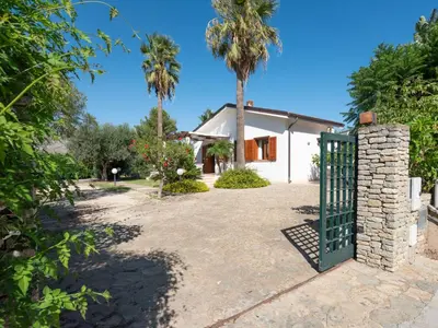 a gate in front of a house with palm trees at Villa New Charme in Castellammare del Golfo