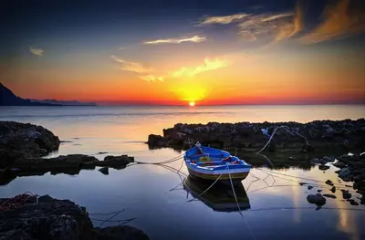 a small boat in the water with the sunset in the background at L'isola di Fimi in Isola delle Femmine