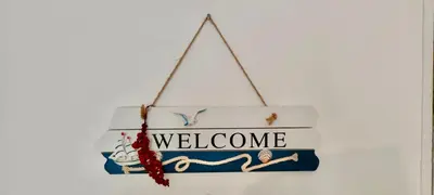 a sign with the word welcome hanging on a wall at L'isola di Fimi in Isola delle Femmine