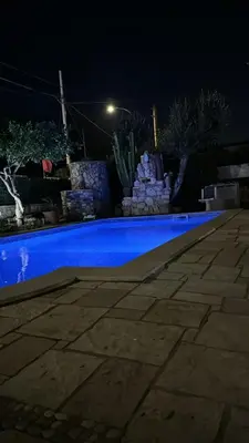 a blue swimming pool in a yard at night at Villa con piscina 