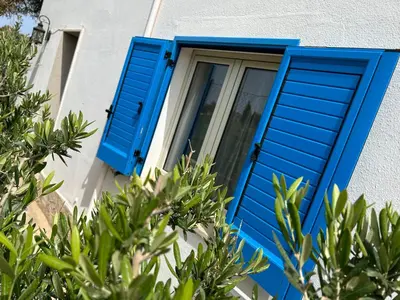 a blue window on a white building with trees at CASE PUNTA MONACO by Trerose Properties con wi-fi e posto auto privato gratuito in San Vito lo Capo