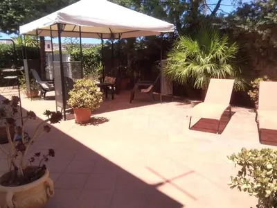 a patio with an umbrella and chairs and plants at VILLETTA MAGNOLIE by Trerose Properties - Villetta indipendente con wi-fi e posto auto gratuito in San Vito lo Capo