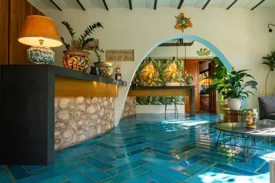 a lobby with a blue tile floor with plants at Magaggiari Hotel Resort in Cinisi