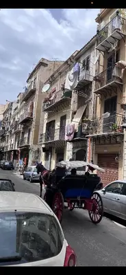 a horse drawn carriage on a city street with buildings at LA CASA DI TABBi in Palermo