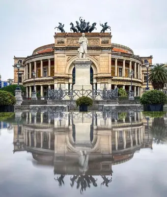 a building with a statue and a reflection in the water at LA CASA DI TABBi in Palermo