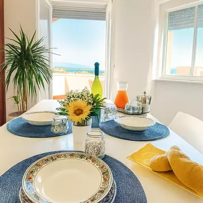 a dining room table with plates and flowers on it at Pasqua 2026 già disponibile Dune Home in una Fantastica soluzione con vista mare dalla veranda in Alcamo