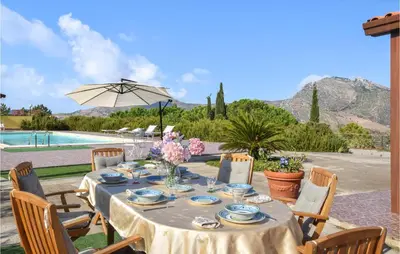 a table with chairs and an umbrella and a pool at Cozy Home In Caccamo With Kitchenette in Caccamo