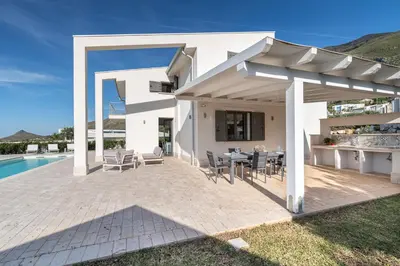 a white house with a patio with a table and chairs at Villa Costamante con piscina privata in Balata di Baida