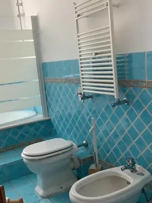 a blue tiled bathroom with a toilet and a sink at Leo's Home in Palermo