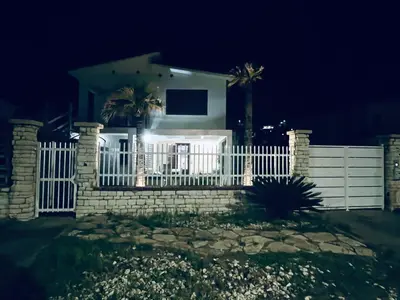 a white fence in front of a house at night at Casa sulla spiaggia in Castellammare del Golfo