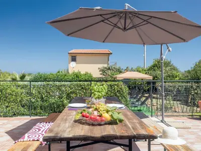 a table with a bowl of fruit and an umbrella at Holiday Home Alice by Interhome in Ficarazzi