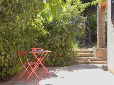 a red table and a chair next to some bushes at Holiday Home Alice by Interhome in Ficarazzi