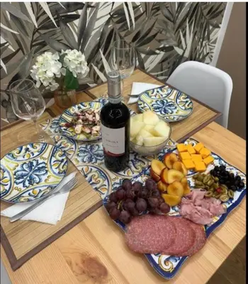 a table with a bottle of wine and plates of food at CapoCathedral apartment in Palermo
