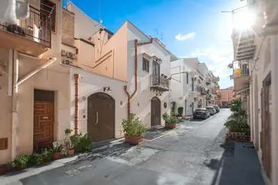 an alley with white buildings and potted plants at Bed and Breakfast Nilu' in Castellammare del Golfo
