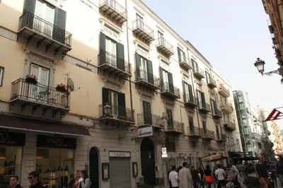 a group of people walking on a street in front of a building at Sole Apartment in Palermo