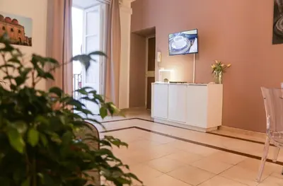 a room with a table and a tv on a wall at Sole Apartment in Palermo