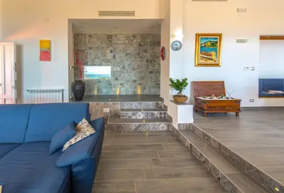 a living room with a blue couch and a stone wall at La Villa di Sofia in Santa Flavia
