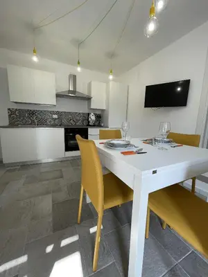 a white kitchen with a white table and yellow chairs at Marosa Casa Vacanze in Torretta
