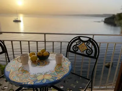 a table with a bowl of fruit on a balcony at Castello a Mare in Castellammare del Golfo