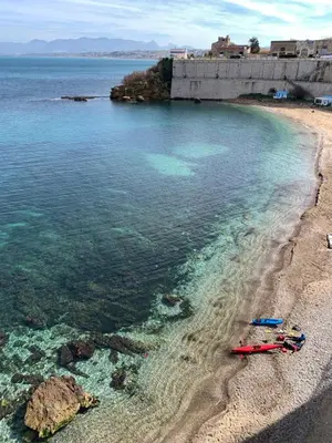 a beach with a group of people laying on the shore at Castello a Mare in Castellammare del Golfo