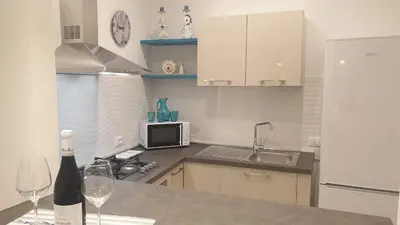 a kitchen with a counter with wine glasses and a refrigerator at Mami Holiday House in Castellammare del Golfo