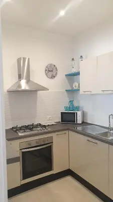 a white kitchen with a stove and a microwave at Mami Holiday House in Castellammare del Golfo